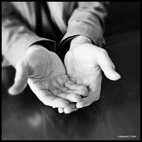 A pair of empty, outstretched hand, shown in a black and white photograph.