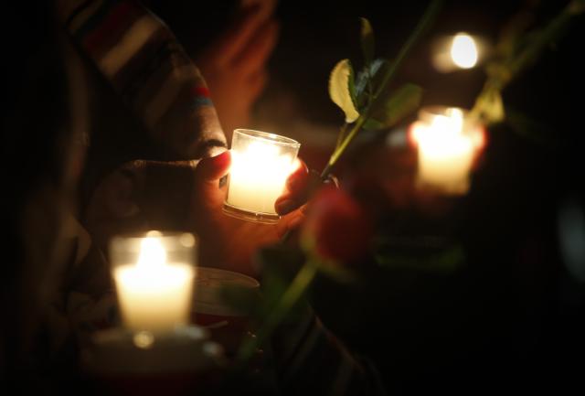 Family and friends of murdered women hold candles at a vigil