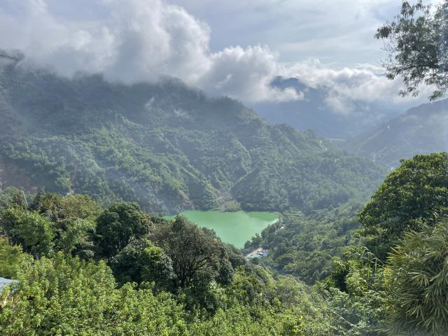 A small lake of water polluted by industrial mining in the Philippines, surrounded by lush green hills.