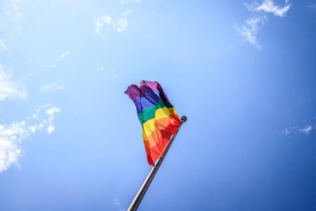 The rainbow-coloured pride flag flies against a blue sky