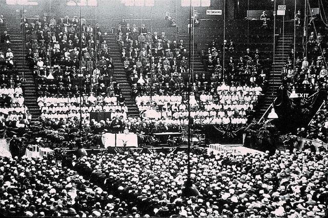 Hundreds of people fill an arena in a black and white photo from 1925.
