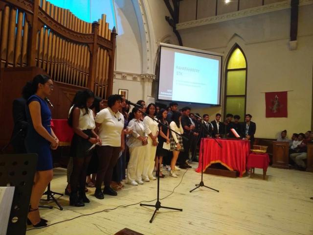 A group of young people from Madagascar sing in a choir at the front of a church.
