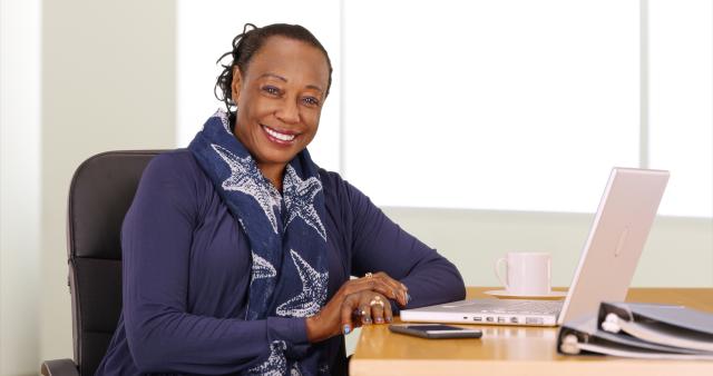 A black businesswoman poses for a portrait at her desk