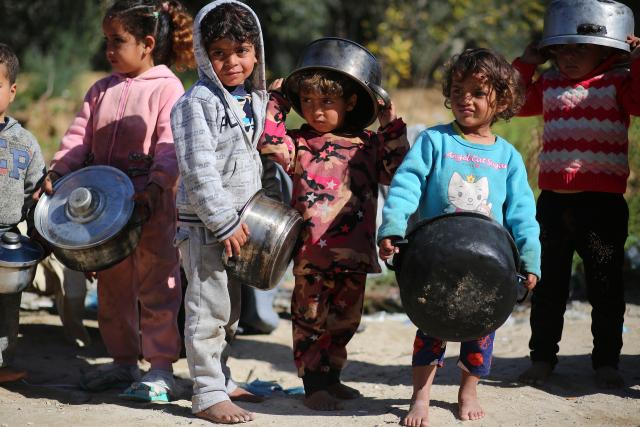 Row of very young Palestinian children holding cooking pots