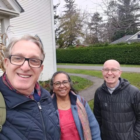 Samer Laham, Annie Namala, and Eric Hebert-Daly pose in front of a church