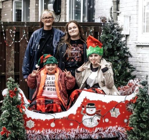 A family of four poses in front of a Christmas tree