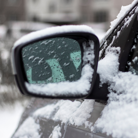 Side mirror on car covered in snow