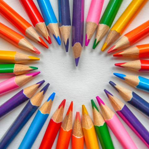 Multicoloured pencils arranged to form a heart