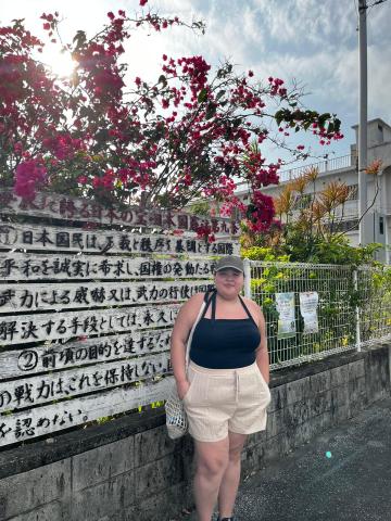 Ashley Keeping stands in front of a sign in Japanese 