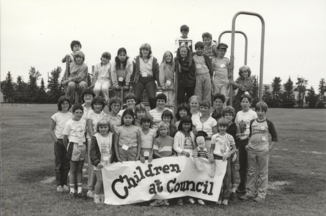 Children posting with a sign reading "Children at Council", circa 1984