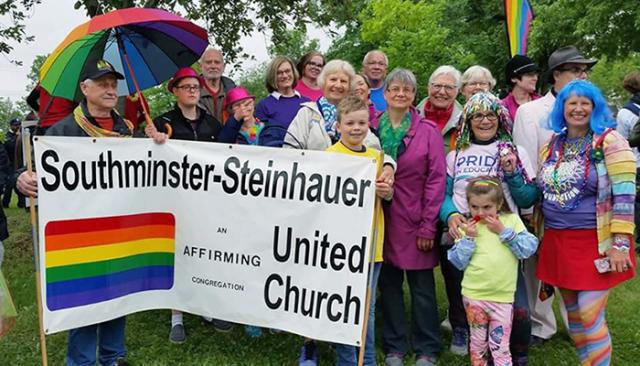 Members of Southminster-Steinhauer United Church carrying their pride sign