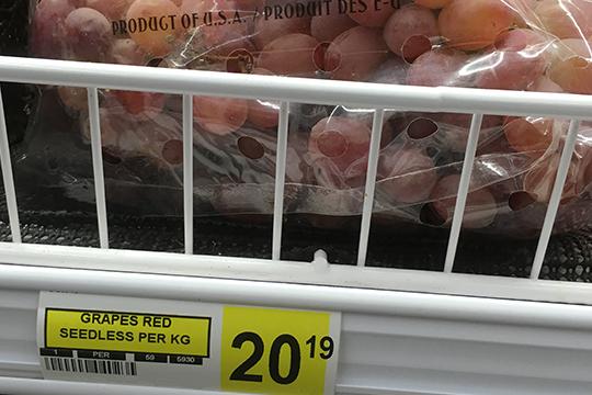 A bag of grapes on a grocery store shelf.