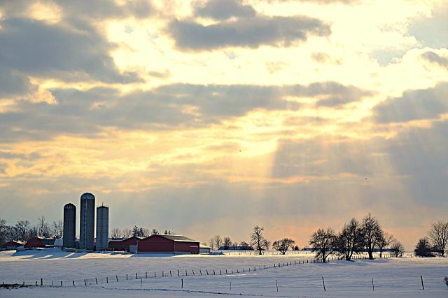 Sunbeams coming through the clouds over an Alberta farm.