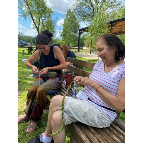Two women braid sweetgrass at the Sandy-Saulteaux Spiritual Centre
