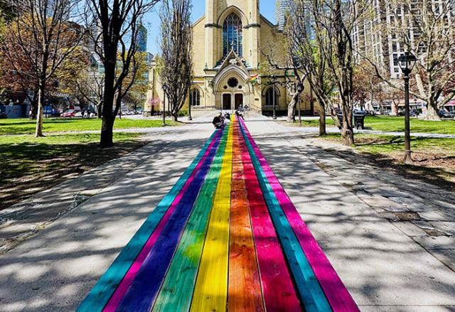 A rainbow coloured 100 foot table in front of the historic Metropolitan United Church Toronto