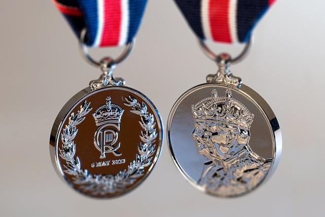 Both sides of a silver medal featuring the face of King Charles and the King's crest.