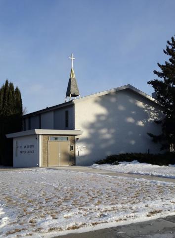 A small white church in front of a snowy lawn.