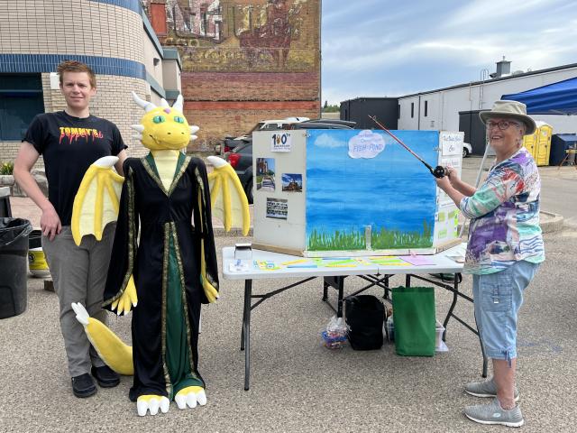 Tommy Kirk, Dixie the dragon, and Linda Stumpf standing next to the fish pond and table