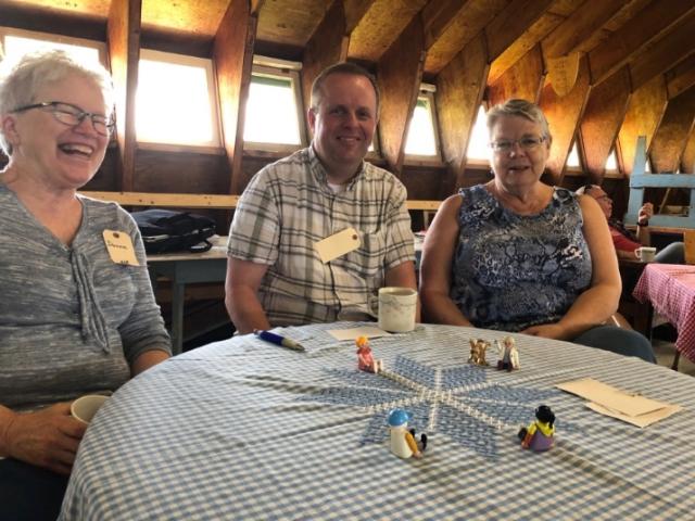 Three smiling people sitting at a round table.