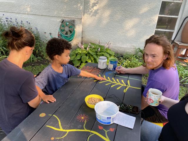 A man and a young boy painting a picnic table.