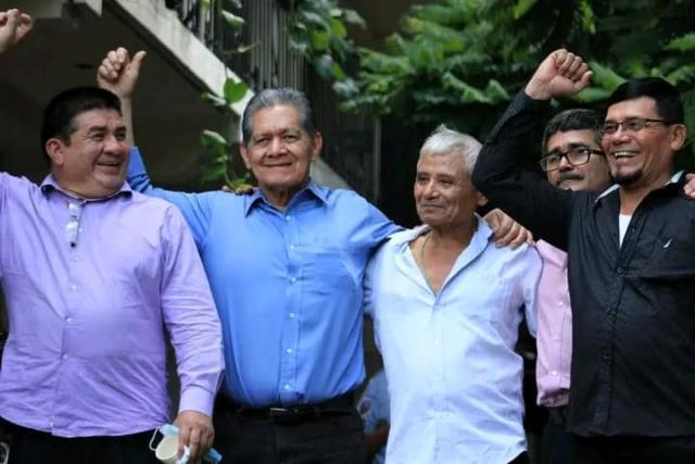 Five Salvadoran men embrace and raise fists in a celebratory gesture