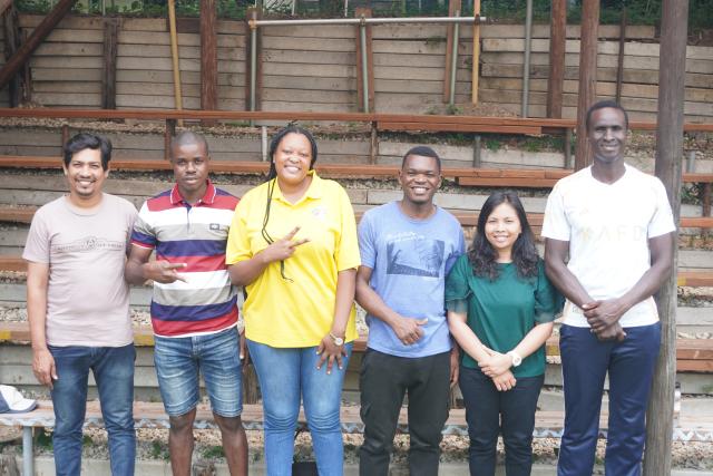 A group of individuals of various ethnicities standing in front of planters.