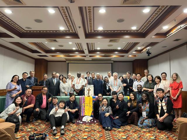 A large group photo in a conference room with several subject wearing religious garments.
