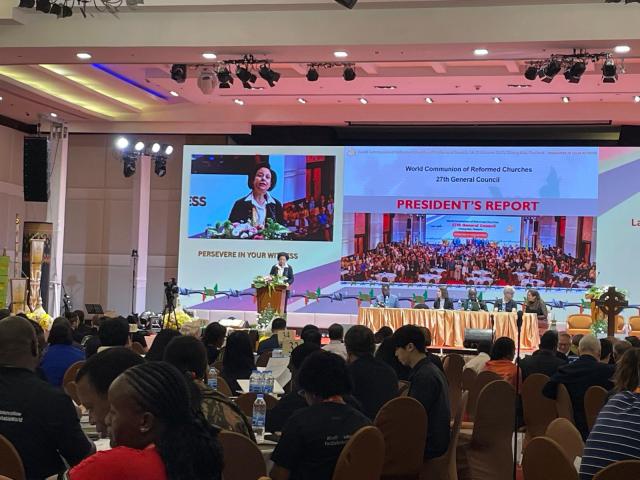 WCRC President Rev. Dr. Najla Kassab giving her report onstage in a conference room