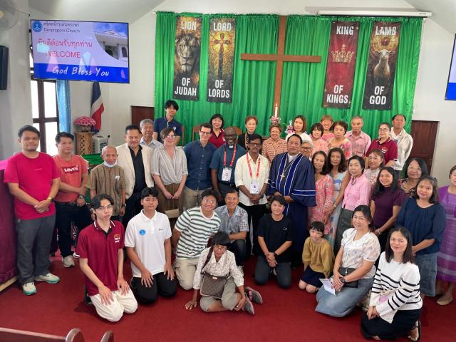 A smiling group stands in front of a crucifix in a church