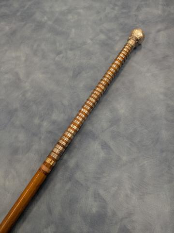 A wooden staff with silver engraved nameplates wrapped around much of it, and a silver head.