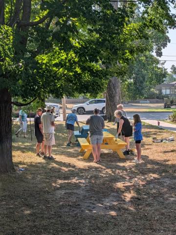 A group of people playing by two colourful picnic tables