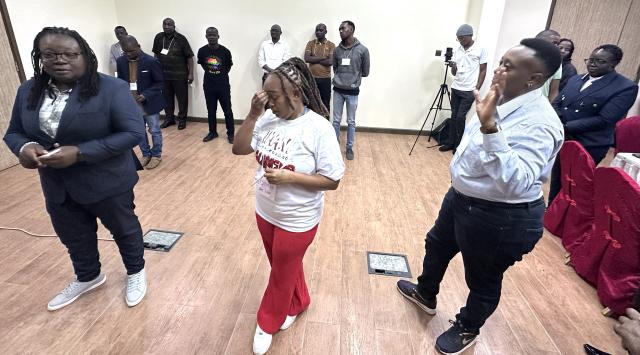 A group of people standing in various point across a meeting room floor 