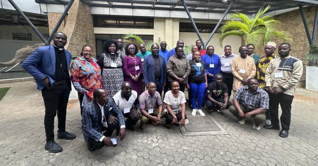 A group of African clergy and lay people outside of a building