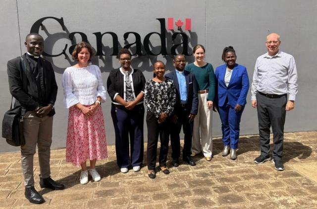 A group of people posing for a photo in front of a sign that reads "Canada"
