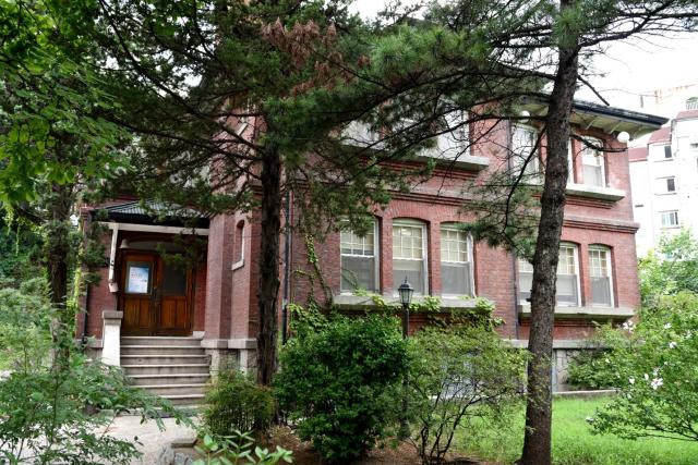 A large red-brick house behind trees