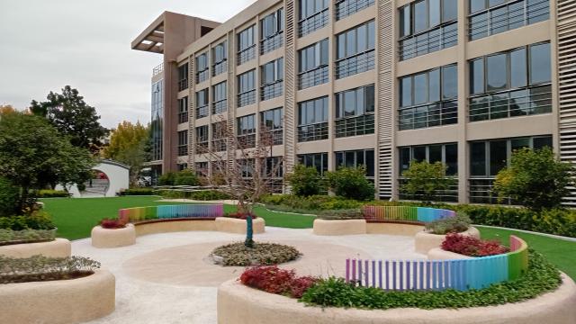 A glass and concrete building with a garden in front of it