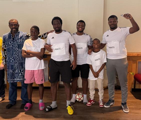 A group of boys and men pose in athletic clothes, with the word "Haiti" on their shirts