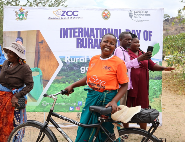 A smiling African woman poses with a bicycle