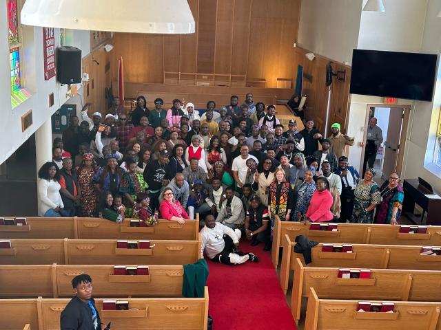A group photo of a large amount of Africans smiling at the front of a church