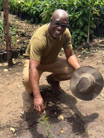 A smiling man planting a tree in dirt