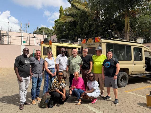A group photo outdoors in front of lush greenery