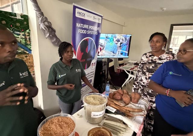 A group of people standing around a table with produce and grains on it