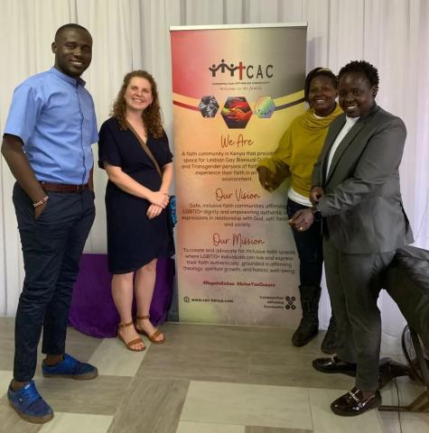 A group of four people smiling in front of a banner with info on CAC