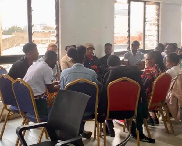 A circle of people sitting in chairs and talking in a conference room