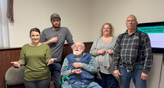 A group of five people demonstrating American Sign Language