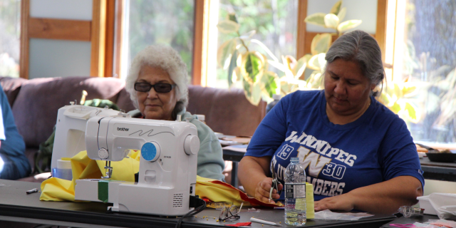 Two women sit at a craft table. 
