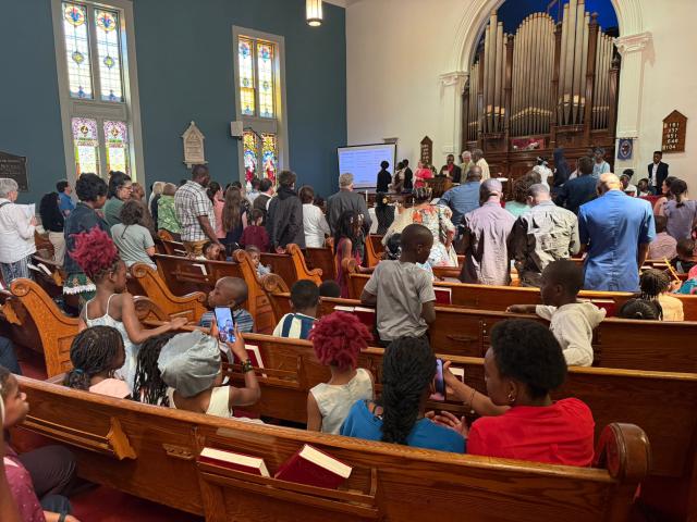 A church full of people standing and sitting