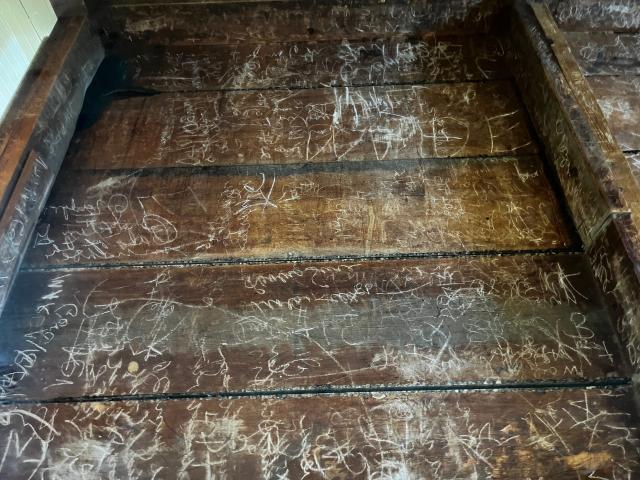 The underside of a table with words and drawings scratched into it