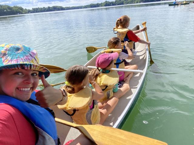 Children and an adult paddle a canoe