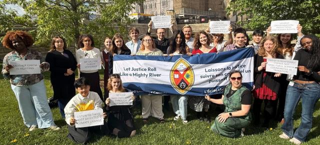 A group of youths hold up signs with slogans calling for climate leadership, as well as a large United Church banner